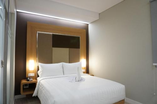 a bedroom with a large white bed and a mirror at Front One Hotel Papua Lestari in Timika