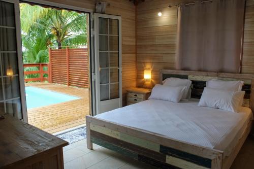 a bedroom with a bed and a sliding glass door at Villa Barthelemy - Gite 2 in Goyave