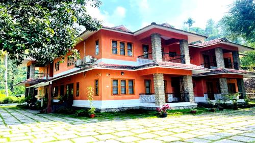 an orange house with a courtyard in front of it at Chembra Adobe in Kalpetta