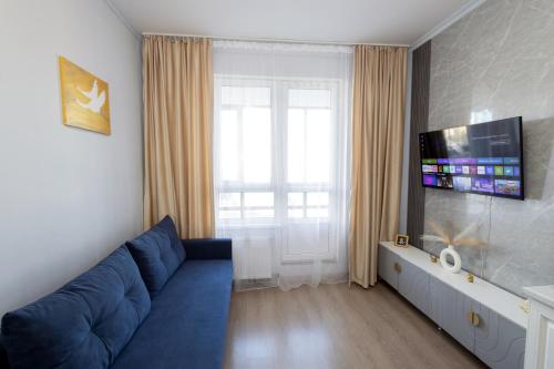 een woonkamer met een blauwe bank en een tv bij Central Lifestyle in Astana