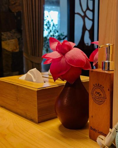 a red flower in a brown vase on a table at The Symbol of Ella in Ella