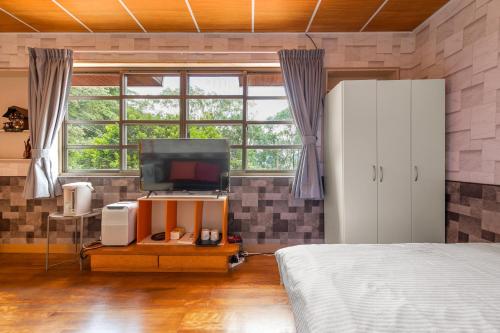 a bedroom with a bed and a tv and a window at Hill Side B&B in Yuchi