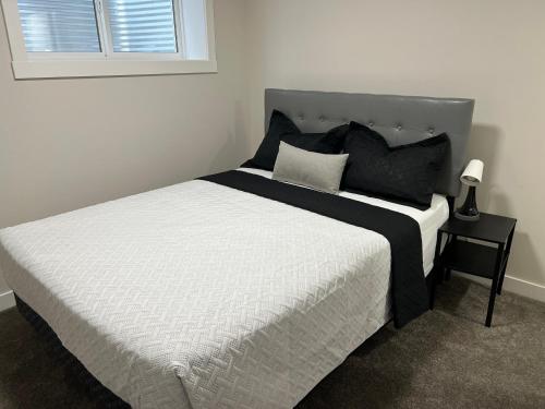 a bed with black and white sheets and a window at Little Heaven 2BR southwest Calgary in Calgary