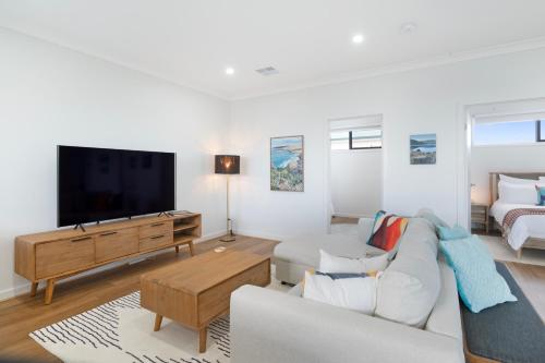 a living room with a couch and a flat screen tv at Ocean Views on Grundy I New Home I Family Friendly in Christies Beach