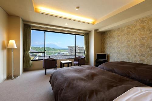 a hotel room with a bed and a desk and a large window at Hotel Shion in Morioka