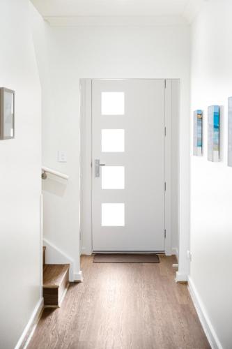 an open door in a room with white walls and wooden floors at Ocean Views on Grundy I New Home I Family Friendly in Christies Beach