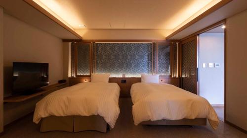 a hotel room with two beds and a flat screen tv at Hotel Shion in Morioka