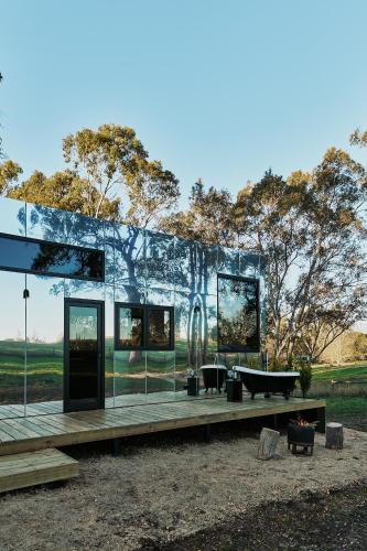 a glass house with a table and a bench at Nestled Cabins