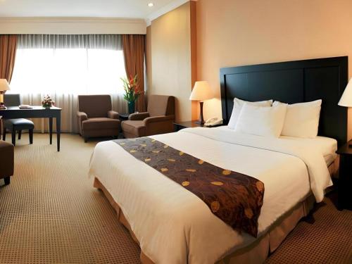 a hotel room with a large bed and a desk at Danau Toba Hotel International in Medan