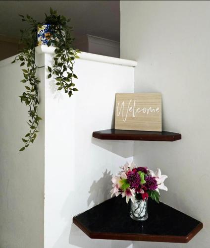 a vase of flowers on a shelf with a welcome sign at Retro Bar Themed Spacious Studio room in Perth