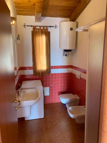 a bathroom with two sinks and a toilet at Апартаменты с великолепным видом на горы in Viddalba