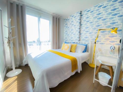 カトゥーにあるLuxury Condo Near Patong Beach & Shopping Mallのベッドと机と窓のある寝室