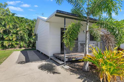 a small white house with a porch and palm trees at Ingenia Holidays Townsville in Townsville