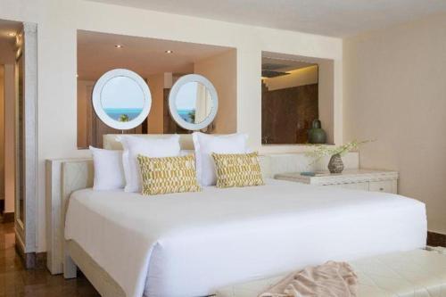 una camera da letto con un grande letto bianco con due specchi di BELOVED PLAYA MUJERES - ALL INCLUSIVE- ADULTS ONLY a Cancún