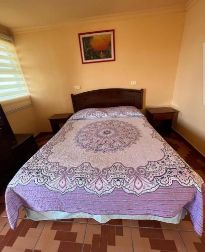 a bedroom with a bed with a purple comforter at Residencial Mi casa in Coquimbo