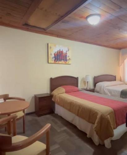 a bedroom with two beds and a table and a table at Residencial Mi casa in Coquimbo