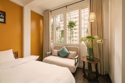 a bedroom with a bed and a chair and a window at Oh Trendy Homes Hoan Kiem PNL3 in Hanoi