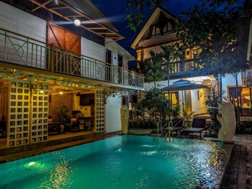 a swimming pool in front of a house at night at Travellers Inn in Phumĭ Réach Born
