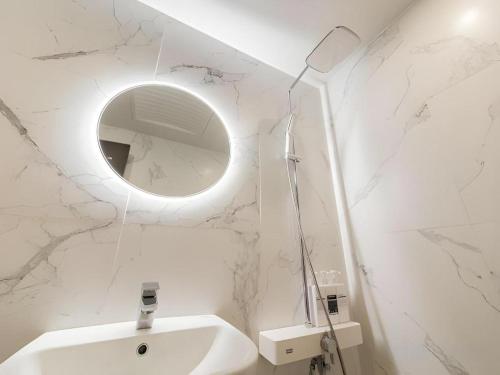 a white bathroom with a sink and a mirror at Plain Hotel in Chuncheon