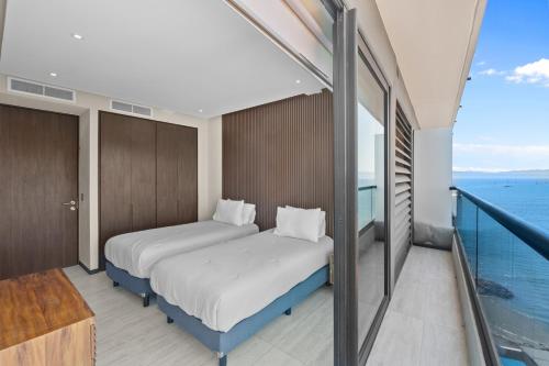two beds in a room with a balcony at Unforgettable Holidays by the Ocean in Cruz de Huanacaxtle