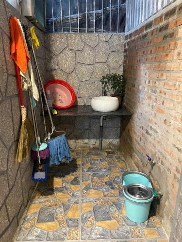 a corner of a brick wall with a bucket and broom at Subin Homestay Hue in Thôn Kim Long (1)