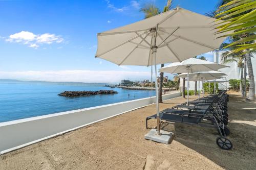a group of chairs and an umbrella on a beach at Unforgettable Holidays by the Ocean in Cruz de Huanacaxtle