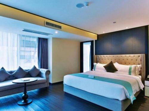 a bedroom with a large bed and a couch at Xana Hotelle Chengdou Xindu Sanhechang Metro Station in Chengdu
