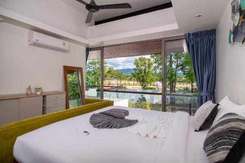 a bedroom with a large white bed and a large window at Bang Tao 6-bedroom large private pool modern Balinese style leisure holiday villa BBQ family group the park in Laguna Phuket