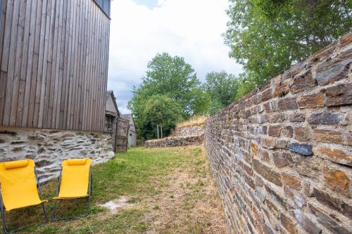 two yellow chairs sitting next to a stone wall at La grange in Les Salces