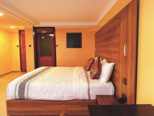 a bedroom with a large bed with a wooden headboard at Karen Plains Hotel Nairobi in Nairobi