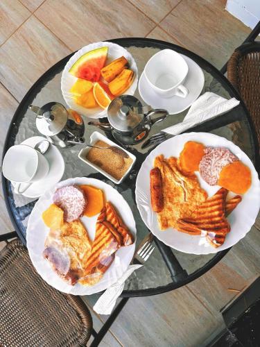 a glass table topped with plates of pastries and fruit at Karen Plains Hotel Nairobi in Nairobi
