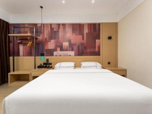 a bedroom with a large white bed and a painting at City Comfort Inn Shiyan Wudang Mountain in Danjiangkou