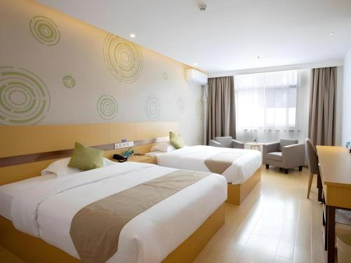 a hotel room with two beds and a desk at GreenTree Inn Linhai Jiangnan Avenue Express in Linhai