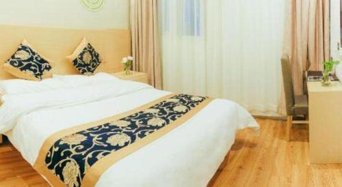 a bedroom with a bed with a blue and white blanket at Green Tree Inn Fengxian New City Metro Station Jiukeshu Art Center in Shanghai