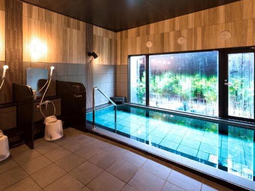 a swimming pool in a room with a large window at Hotel Route Inn Kan-onji