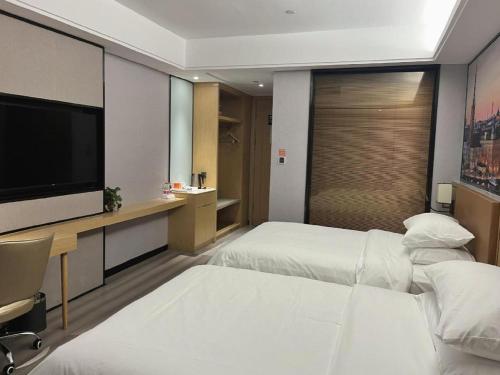a hotel room with two beds and a flat screen tv at Vienna Hotel Jiangxi Shangrao High-Speed Railway Station in Shangrao