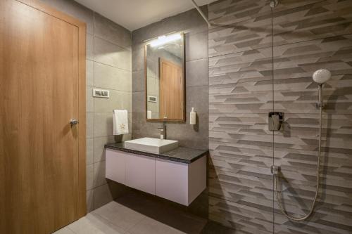 un bagno con lavandino, specchio e doccia di SaffronStays Terra a Verem