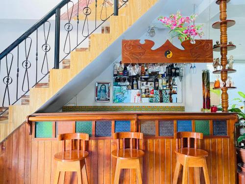 a bar with three stools at a bar with a staircase at Sarisa House in Iquitos