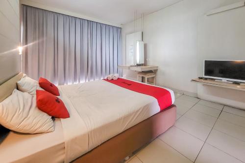 a bedroom with a bed with red pillows and a television at RedDoorz near UPI Setiabudhi Bandung in Bandung