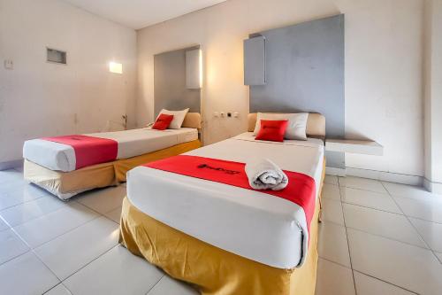 a room with two beds with red and white pillows at RedDoorz near UPI Setiabudhi Bandung in Bandung