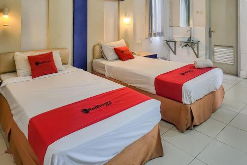 two beds with red and white sheets in a room at RedDoorz near UPI Setiabudhi Bandung in Bandung