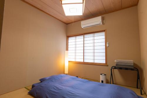 ein Schlafzimmer mit einem blauen Bett und einem Fenster in der Unterkunft guesthouse UZU Sado - Vacation STAY 90684v in Sado
