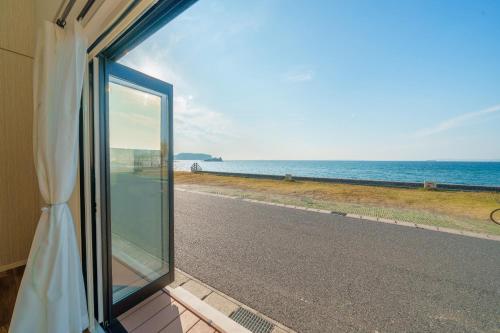 a window with a view of a road and the ocean at Ryushima Ocean View Besso - Vacation STAY 13427 in Minamiboso