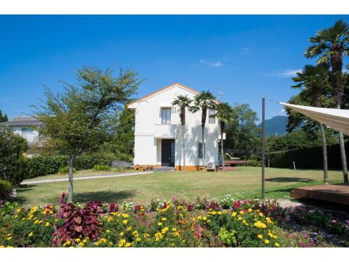 a white house with palm trees and flowers at Glamp House DAISEN Garden - Vacation STAY 97255v in Yonago