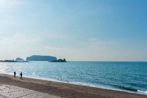 two people walking on a beach near the water at Ryushima Ocean View Besso - Vacation STAY 13427 in Minamiboso