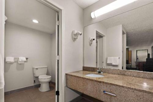 a bathroom with a sink and a toilet and a mirror at Rodeway Inn Lumberton Central in Lumberton