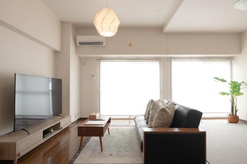 a living room with a couch and a flat screen tv at RIVER WEST Hiroshima 302, 305, 306 - Vacation STAY 54102v in Ōsukachō