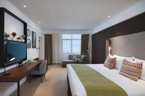 Una habitación de hotel con una cama grande y un escritorio. en Campanile Hotel Shenzhen Bay Convention and Exhibition Center, en Fenghuangwei