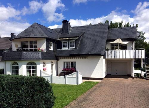 uma casa branca com um telhado preto em Ferienwohnung Bergluft em Winterberg