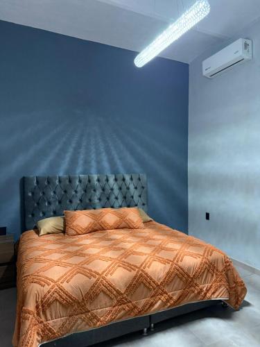 Un dormitorio con una cama con una pared azul. en Sayula Suites Hotel, en Sayula